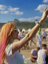 Midsection of woman with arms raised against sky