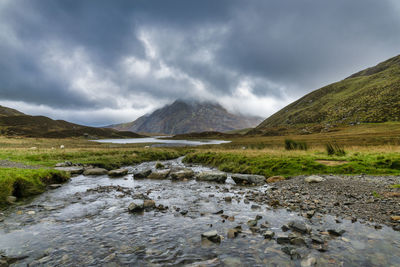 Scenic view of stream by mountains against sky