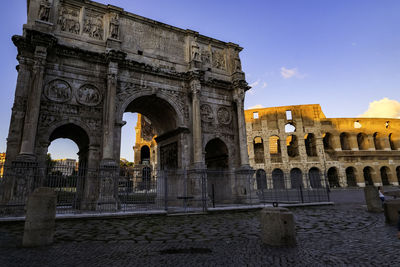 Arco di constantino and colosseum against a clear blue sky during sunset - rome, italy