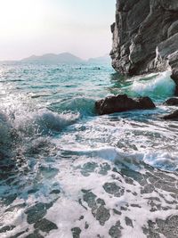 Waves splashing on rocks against sky