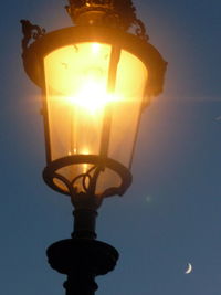 Low angle view of illuminated light bulb against sky