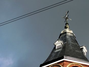 Low angle view of cross on building against sky