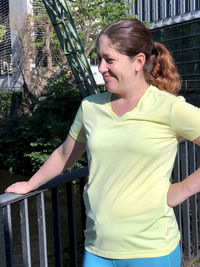 Young woman looking away while standing by railing