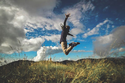 Man jumping on field against sky