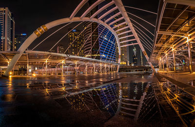 Illuminated bridge over river in city at night