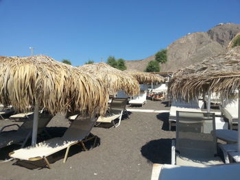 Thatched roofs and lounge chairs on beach during sunny day
