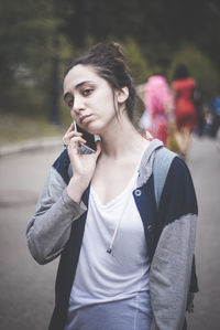 Young woman looking away while standing on mobile phone