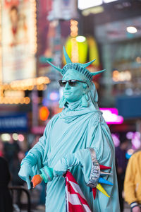 Close-up of statue by illuminated city at night