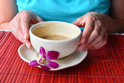 Woman holding coffee cup while sitting at table