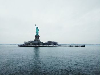 Statue of liberty by hudson river against sky