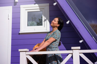 Side view of young woman standing against building