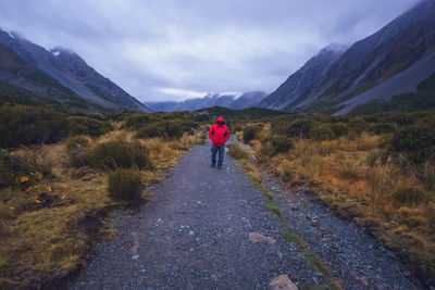 Rear view of man walking on mountain against sky