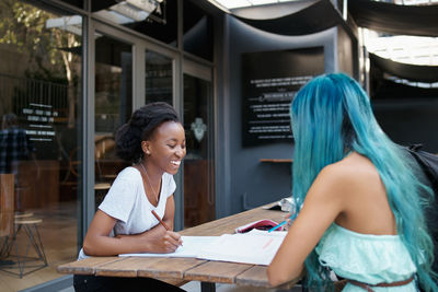 Smiling female friends studying at college campus