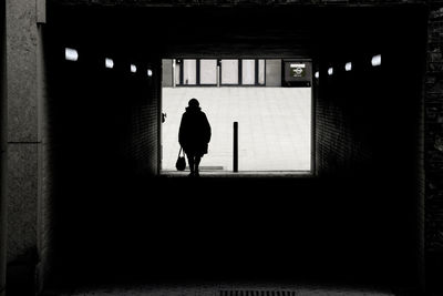 Rear view of silhouette man walking in building