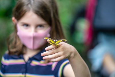 Close-up portrait of girl holding butterfly outdoors