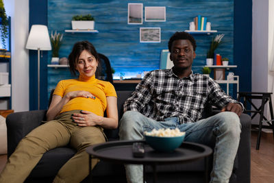 Man sitting with pregnant woman on sofa at home