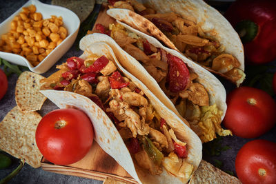 Still life of three fajitas or mexican tacos with meat, pepper, tomato, spicy pepper and nachos