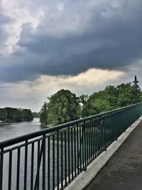 Railing by trees against sky