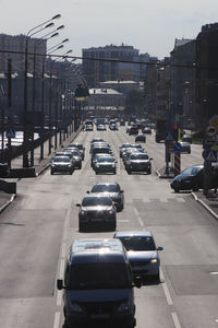 Cars on city street by buildings against sky