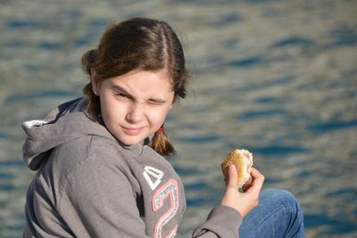 Portrait of cute girl holding food by lake