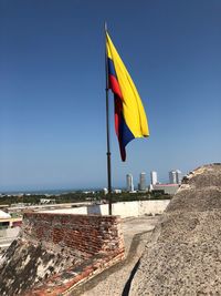 Flag on beach against buildings in city against clear sky