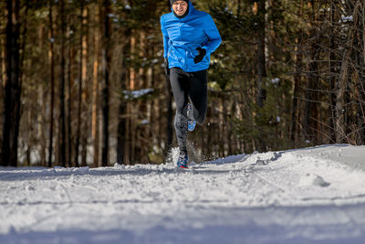 Male runner running on snowy trail in forest