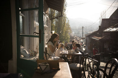 Young woman drinking coffee while sitting on table at cafe