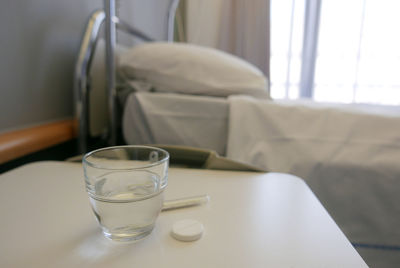 Close-up of drinking glass with pill on table in bedroom