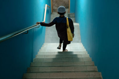 Rear view of man walking on staircase