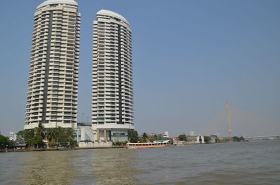 Modern buildings by sea against clear sky