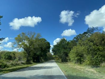 Empty road amidst trees against sky