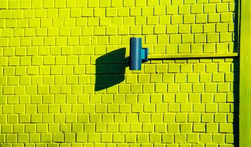 Close-up of yellow umbrella against blue wall