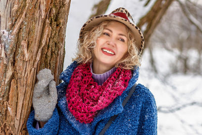 Portrait of young woman standing against tree