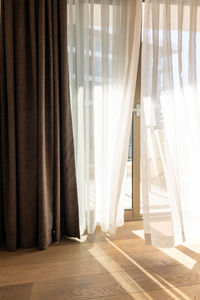 Modern room interior with an open window in minimal style. transparent tulle with morning sun rays 