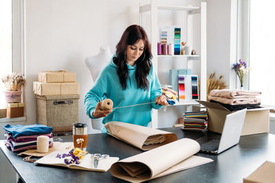 Small business owner woman packs the goods in eco packaging in office, shop.