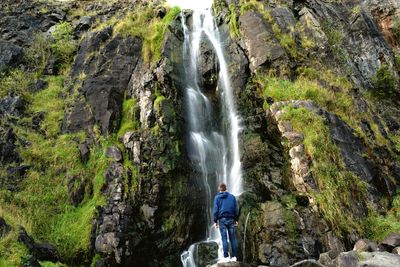 Rear view full length of man standing against waterfall