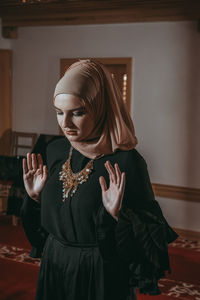 Woman in traditional clothing praying at mosque