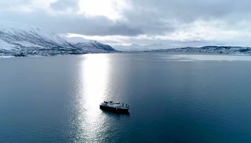 Scenic view of sea and snowcapped mountains against sky