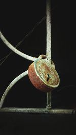 Close-up of rusty hanging on rope against black background