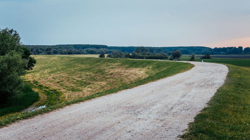 Road amidst field against clear sky