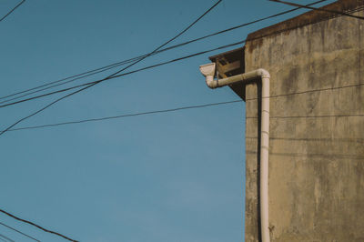 Low angle view of telephone pole against clear blue sky