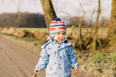 Cute girl wearing warm clothing standing on land