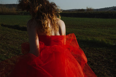 Rear view of young woman wearing red dress while walking on land