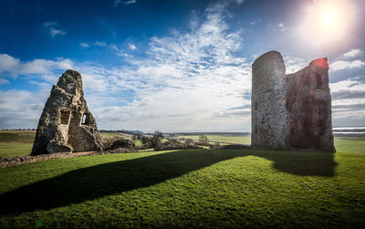 Sun shining over old ruins on grassy field