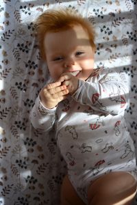 Portrait of cute baby boy lying on bed at home