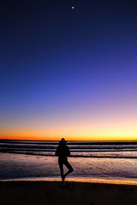 Silhouette of people standing on beach at sunset