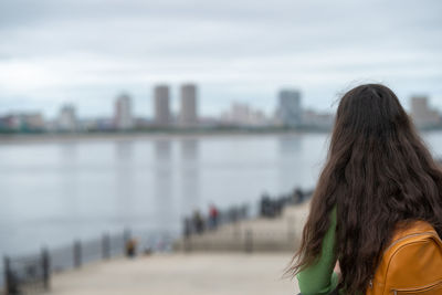 Rear view of woman standing against lake