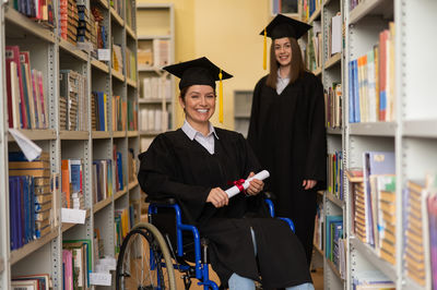 Low angle view of woman wearing graduation in library