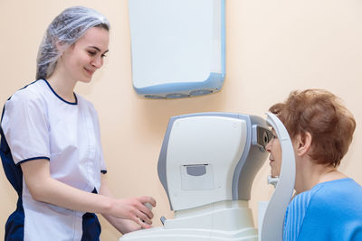 A girl optometrist examines the eyes of a patient using special modern equipment