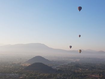 Hot air balloons flying over landscape against clear sky